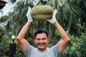 Aziatische man met durian fruit boven zijn hoofd
